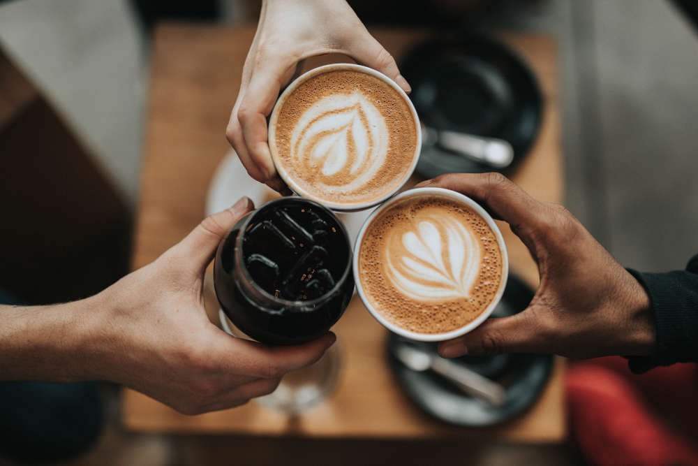 three hands holding coffees
